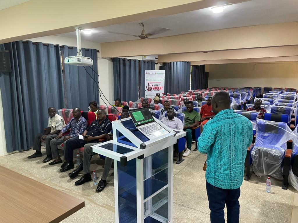 A facilitator addresses community members and security stakeholders at a project meeting
